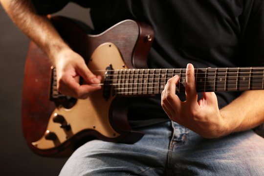 Young musician playing electric guitar close up