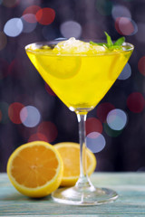 Glass of cocktail with ice on blurred lights background