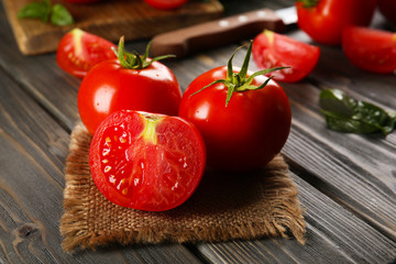 Red tomatoes and knife on napkin on wooden background