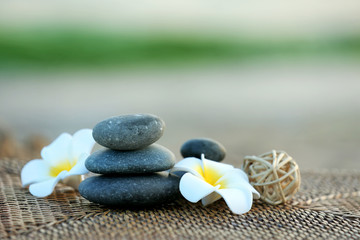 Fototapeta na wymiar Composition of pebbles and fragipani flower on wattled background