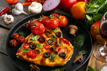 Decorated pizza with vegetables on pan on wooden background