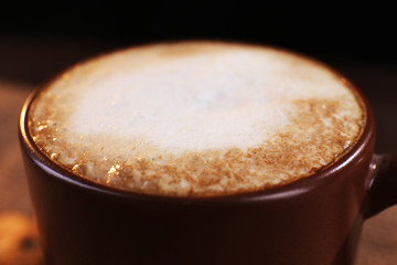 Cup of coffee with milk foam on wooden table, close up