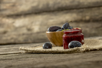 Still life with a jar of home made plum marmelade and wooden bow