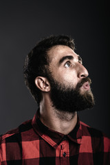 Portrait of a happy young man with beard whistling against gray