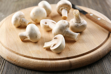Champignon mushrooms and a knife on wooden background