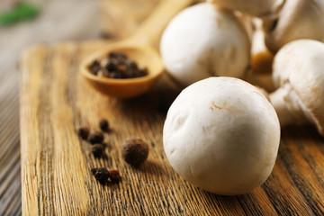 Champignon mushrooms, a spoon and spices on wooden background