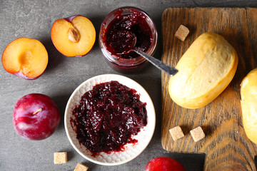Tasty jam in the jar and on the plate, plums, crackers and fresh buns close-up