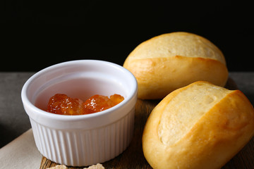 Tasty jam in bowl, crackers and fresh buns close-up