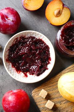 Tasty jam in the jar and on the plate, plums, crackers and fresh buns close-up