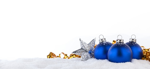 Blaue Weihnachtskugeln, silberner Weihnachtsstern und goldenes Geschenkband im Schnee