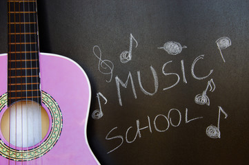 Music school for children with purple guitar closeup on blackboard background