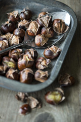 Roast chestnuts in a baking tray with a metal spoon