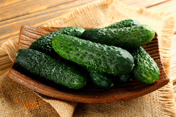 Fresh cucumbers in rustic bowl on  wooden background