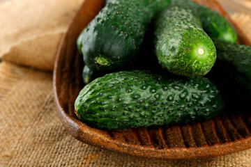 Fresh cucumbers in rustic bowl on  wooden background