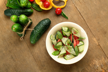 Vegetable salad with cucumbers on wooden background