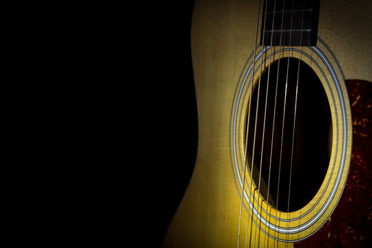 Acoustic guitar isolated on black background, horizontal view, low key image