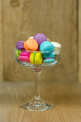 colorful macaroons in glass on wooden table