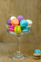 colorful macaroons in glass on wooden table