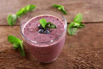 Fresh blueberry yogurt decorated with berries and mint on wooden background