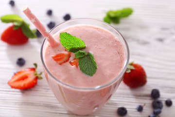 Fresh strawberry yogurt with berries around on light wooden background, close up