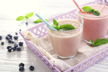 Tasty strawberry, blueberry and milk yogurt on server in a row against light wooden background