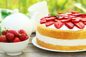 Sweet cake with strawberries on plate on grey wooden background