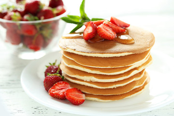Tasty pancakes with strawberry on white wooden background