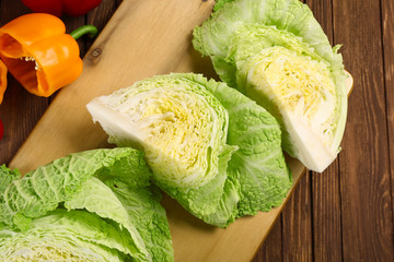 Cut savoy cabbage and pepper on wooden cutting board closeup