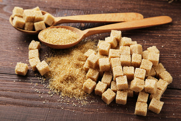 Brown sugar in spoon on brown wooden background