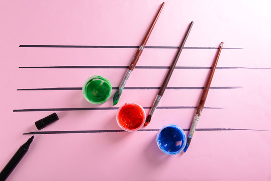 Creative music notes made of colourful paints on pink background