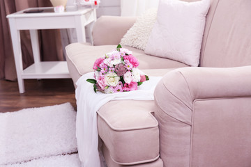 Wedding bouquet and bridesmaid dress on sofa in room