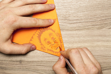 Fototapeta premium Monkey business for monkey`s year. A man carves the snowflake, with monkey face, out of paper