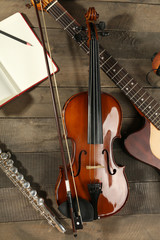 Fototapeta premium Electric guitar, violin, soprano saxophone and book on wooden background