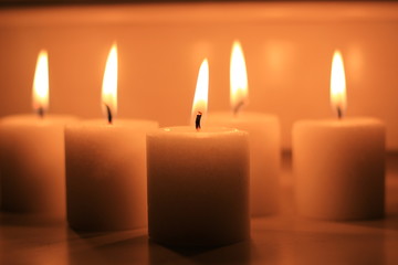 Holiday candles burning on a white background and reflected.