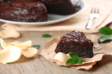 Piece of chocolate cake decorated with flowers on brown wooden table