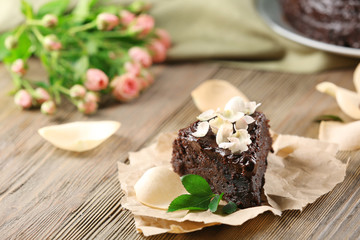 Piece of chocolate cake decorated with flowers on brown wooden table