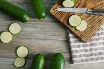 Fresh sliced zucchini on cutting board, on wooden background