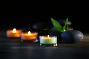 Spa stones and candles on dark background