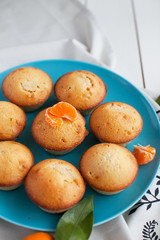 muffins with tangerines in a blue plate on a white table