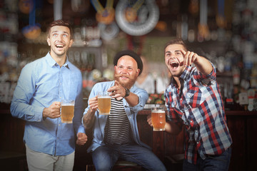 Young men with beer rejoice the victory of their favorite team in the pub