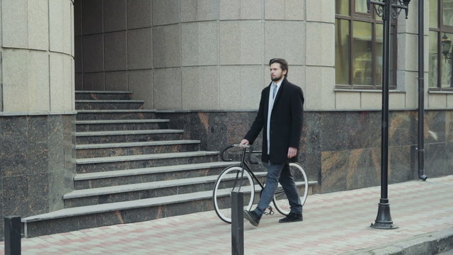 handsome businessman walking with his bicycle in downtown
