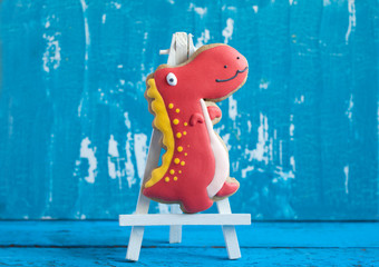 Homemade gingerbread cookie in the shape of dinosaurs on a wooden background. Space for text and selective focus.