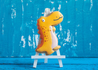 Homemade gingerbread cookie in the shape of dinosaurs on a wooden background. Space for text and selective focus.