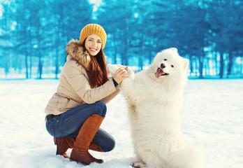 Happy woman owner playing with white Samoyed dog in winter day