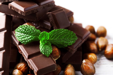 Chocolate pieces with nuts on color wooden background