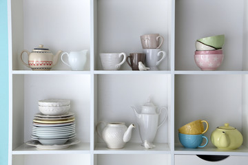 Different clean dishes on wooden shelves