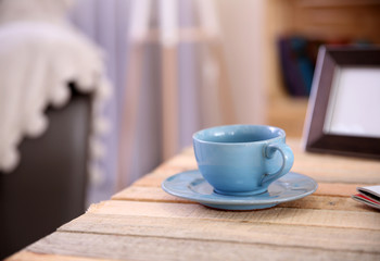 Cup with hot drink on coffee table, on home interior background