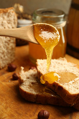 Honey dripping on fresh bread on wooden background