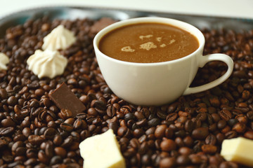 Cup of coffee with sweets and coffee beans on a tray