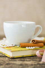 White cup of chamomile tea and book on table.